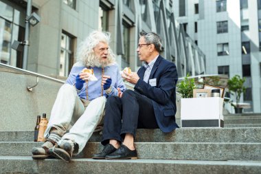 Buruşuk adamın gözlük ve burger yemek güzel mavi gömlek giydiğini