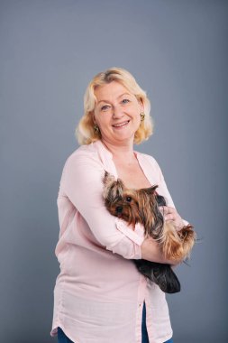 Mutlu orta yaşlı bir kadın köpeğiyle poz