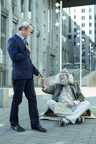 Welvarende zakenman helpende straat persoon — Stockfoto