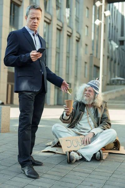 Riche homme d'affaires méthodique donnant un peu d'argent au pauvre homme — Photo