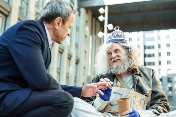 Podpůrnou cizinec dává bezdomovce peníze na jídlo — Stock fotografie