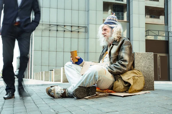 Poor starving man in tattered clothes sitting outside — Stock Photo, Image