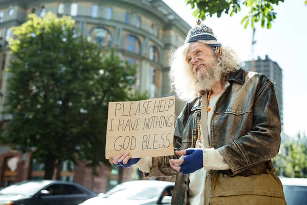 Långhåriga hemlös man står nära trafik som ber om hjälp — Stockfoto