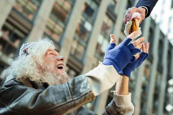 Senzatetto che indossa guanti blu frantumati guardando il cibo — Foto Stock