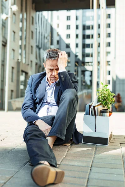 Mann im schwarzen Anzug sitzt auf dem Boden vor dem Büro — Stockfoto