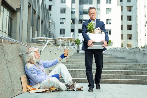 Descargar - Un hombre despedido pasando por un vagabundo rogando por dinero — Imagen de stock Un hombre despedido pasando por un vagabundo rogando por dinero — Foto de Stock