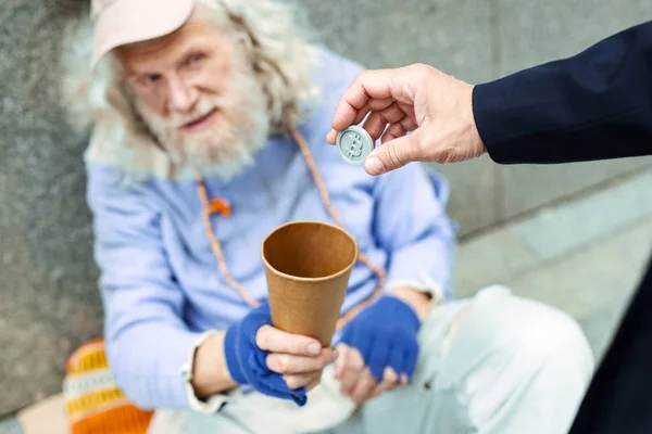 Empresário útil colocando token no copo para homem de rua — Fotografia de Stock