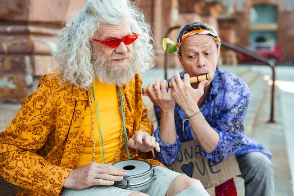 Dlouhé vlasy hippie zářivě žluté košili hraje na bicí — Stock fotografie