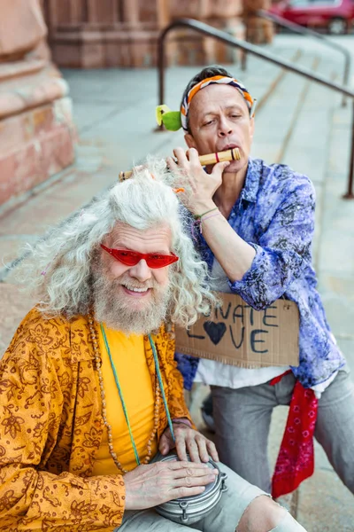 Gülümseyen hippi arkadaşı katılmadan sarı çiçekli gömlek giymiş