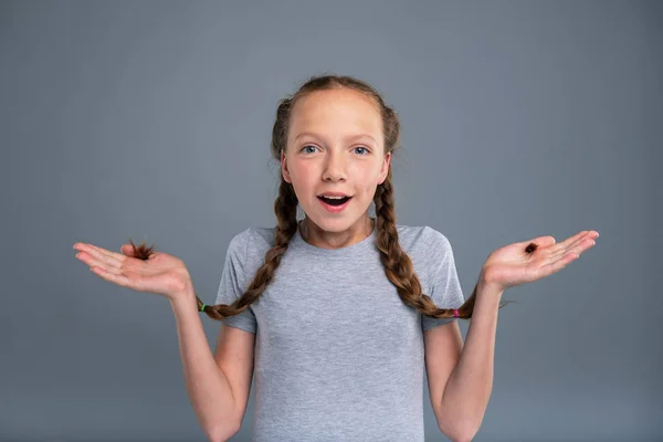 Schattige tienermeisje houden twee vlechten en schouderophalend — Stockfoto