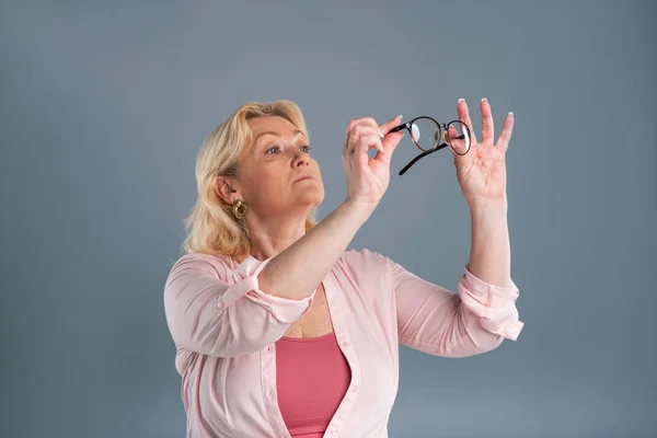 Agradable mujer mayor comprobar la limpieza de las gafas — Foto de Stock