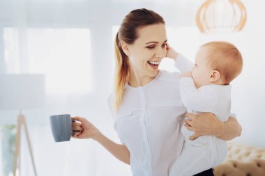 Bebeğini kucaklayan neşeli kadın kişi