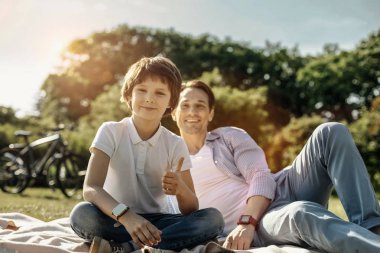 Başparmak gösterilmesini ve babasıyla birlikte oturan çocuk