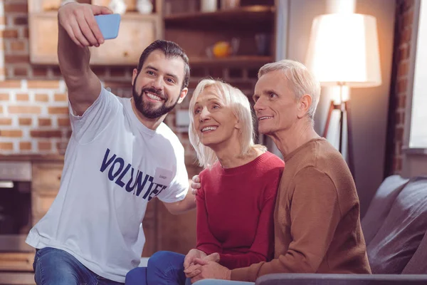 Voluntário alegre usando gadget ao tirar foto — Fotografia de Stock