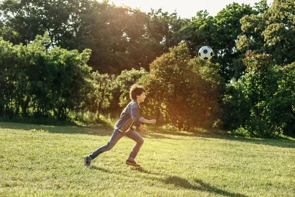 Garoto excitado correndo atrás da bola na natureza — Fotografia de Stock