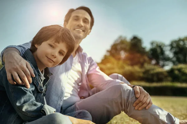 Gülümseyen baba ve sarılma ve oturan oğlu