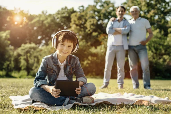 Niño sentado con su tableta y auriculares —  Fotos de Stock