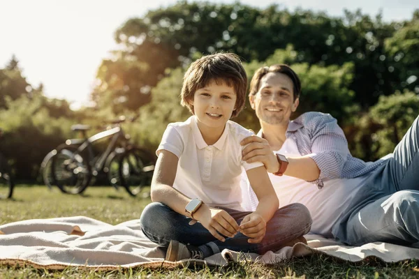 S úsměvem chlapce, který seděl na trávě se svým otcem — Stock fotografie