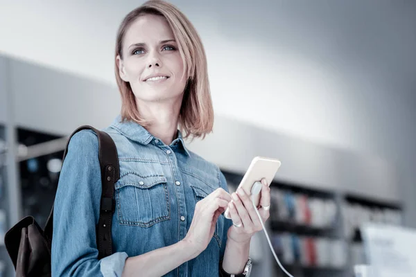 Trevlig omtänksam kvinna står med en smartphone — Stockfoto