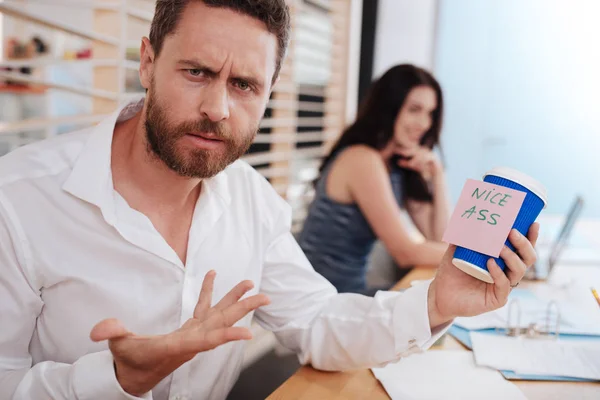 Hombre sorprendido sosteniendo una taza con una pegatina —  Fotos de Stock