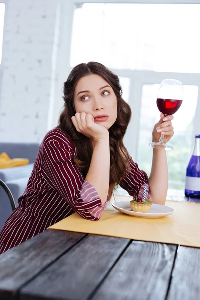 O femeie frumoasă care stă în sufragerie ţinând pahar de vin — Fotografie, imagine de stoc