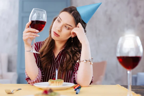 Пессимистичная темноволосая женщина смотрит на бокал вина — стоковое фото