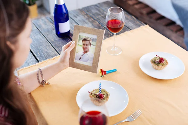 Woman looking at photo of her husband waiting for him — Stock Photo, Image