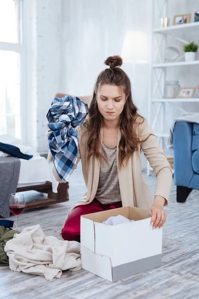 Dark-haired woman putting clothes of ex husband into box — Stock Photo, Image