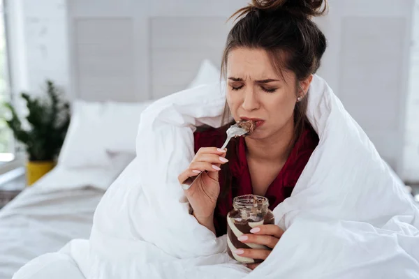 Woman with messy hair eating chocolate and crying — Stock Photo, Image