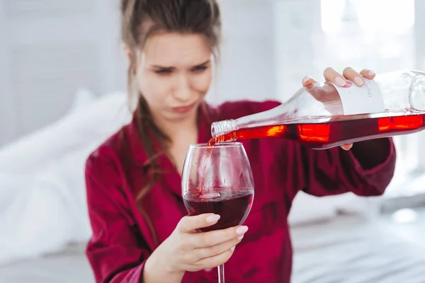 Эмоциональная женщина наливает красное вино в свой бокал — стоковое фото