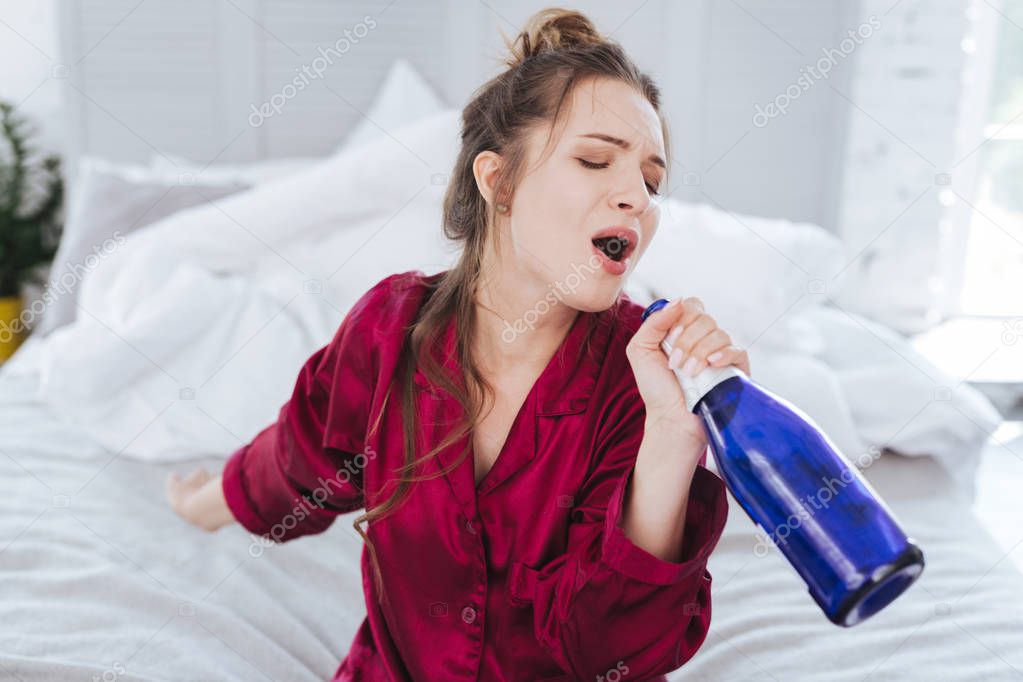 Charming funny woman singing holding bottle of wine