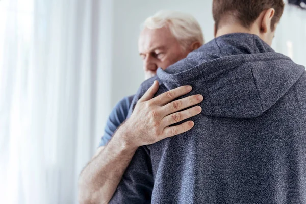 Reflekterande senior man kramas man — Stockfoto