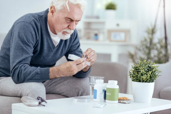 Концентрированный пожилой человек, принимающий таблетки — стоковое фото