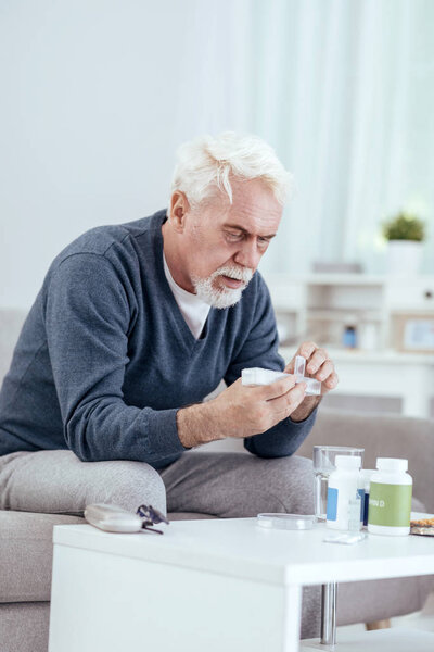 Focused senior man counting pills