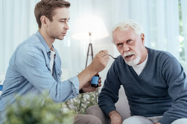 Pozorný člověk dávat lék na starší muž — Stock fotografie