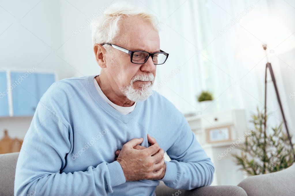 Focused senior man having heart problem
