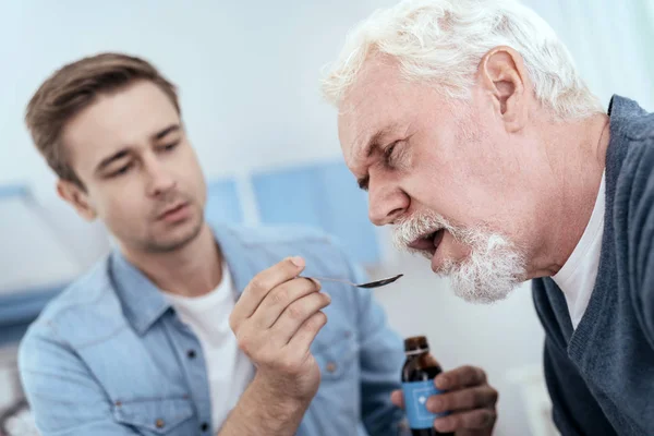 Appealing senior man swallowing drug — Stock Photo, Image