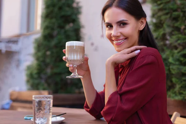 Красивая женщина широко улыбается, когда пьет свой латте — стоковое фото