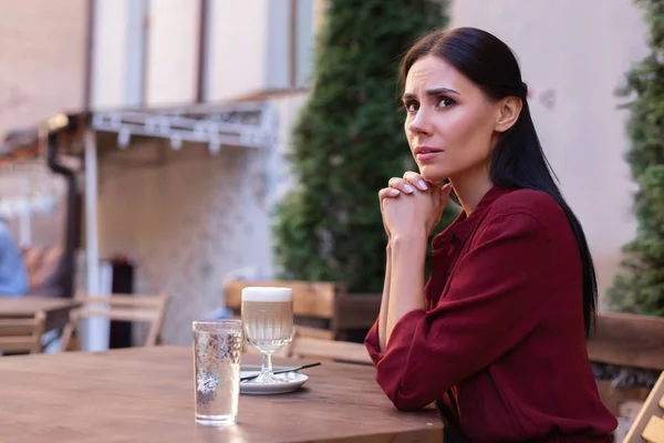 Worried woman. Dark-haired woman feeling rather worried while waiting for her boyfriend for evening date