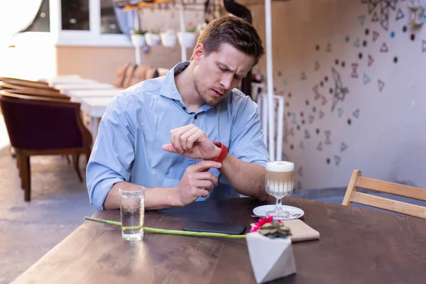 Handsome man looking at his nice red wrist watch — Stock Photo, Image