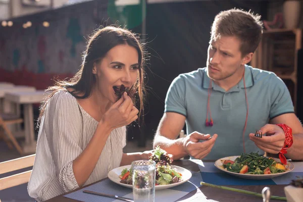 Blonde-haired man kijken naar zijn vriend salade met handen eten — Stockfoto