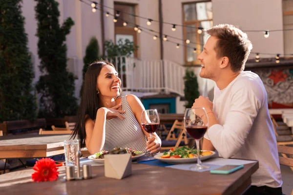Dark-haired woman laughing with her man sitting on fancy terrace — Stock Photo, Image