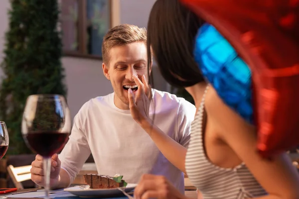 Funny woman putting some sweet cream on nose of her boyfriend — Stock Photo, Image