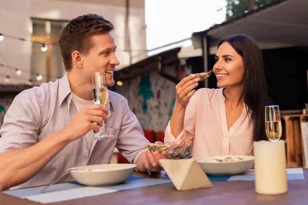 Мужчина в полосатой рубашке пьет шампанское и ест устрицы с женой — стоковое фото