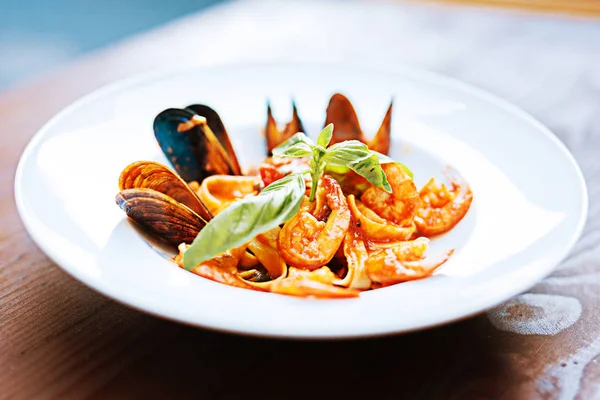 Makarna midye ve beyaz tabak içinde yalan roka ile