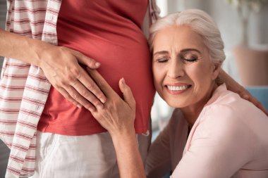 Kulağı hamile karın yakınındaki koyarak güzel çıplak makyaj ile Olgun kadın