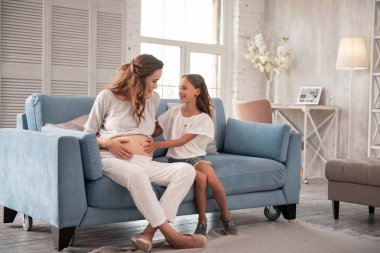 Sevimli küçük kızını hamile anne yakınındaki rahat kanepe oturma