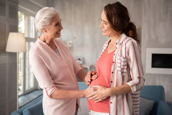 Good-looking smiling expecting woman talking to her aunt — Stock Photo, Image