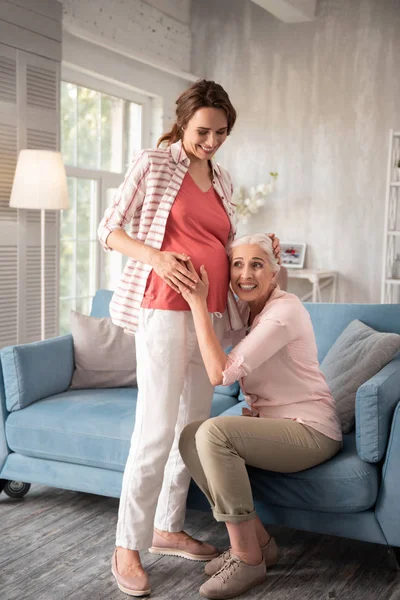 Зріла жінка відчуває себе надзвичайно здивованою, побачивши свою вагітну племінницю — стокове фото