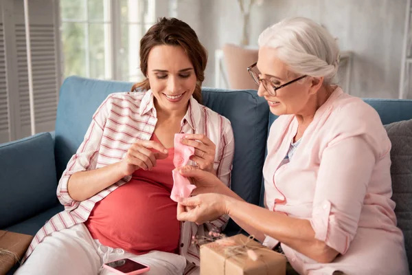 Aged woman wearing glasses looking at little baby socks — Stock Photo, Image